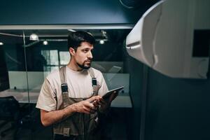 Technician evaluates equipment with a tablet in a modern office environment during working hours photo