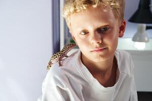 Boy interacts with leopard gecko in cozy indoor setting during afternoon photo