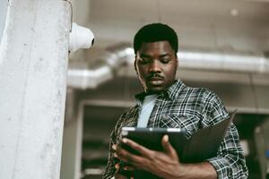 Young man reviewing documents on tablet while standing in modern workspace with industrial design elements photo