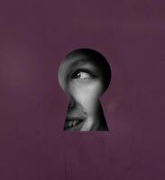 View through a keyhole reveals a smiling face, showcasing curiosity and intrigue in a vibrant setting photo