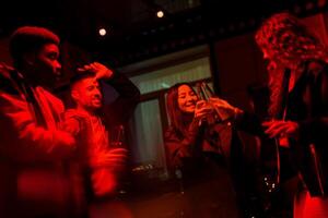 Friends celebrate together at a lively gathering with drinks in a dimly lit venue during an evening party photo