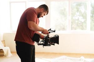 Filmmaker adjusting camera equipment in a bright studio during a creative session photo