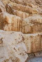 Large ancient limestone blocks form the base of a historical structure in the desert, showcasing impressive quarrying techniques used in construction photo