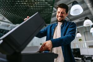Man operating printer in modern office environment during working hours photo