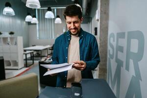 Office worker reviewing printed documents in modern workspace while smiling during a productive day photo