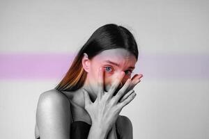 Portrait of a woman expressing emotion with hands covering her face in a minimalist setting during daylight photo