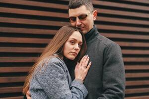 Couple sharing a warm embrace against a wooden backdrop on a cool day in a city setting photo