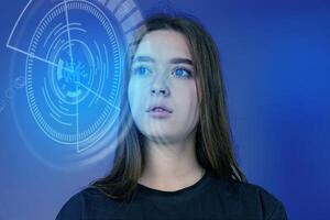Young woman with blue eyes gazing into futuristic digital interface in a studio setting photo