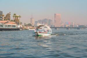 Boats navigate the Nile River with Cairo's skyline in the background during a clear day photo