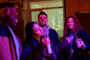 Friends enjoying a lively gathering indoors at night with colorful lights and drinks in hand photo