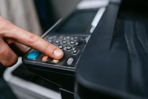 Button press on a multifunction printer for scanning documents in an office setting during daytime photo