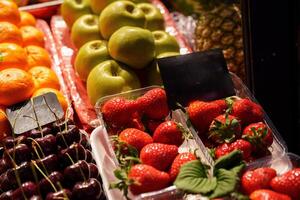 Colorful fruit display showcasing fresh strawberries, cherries, green apples, and vibrant oranges at a local market during early afternoon hours photo