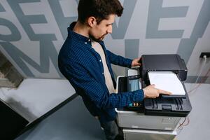 Office worker using a multifunction printer to print documents in a modern workspace photo