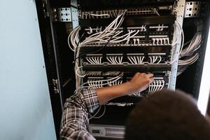 Technician managing network cables in a server room during the afternoon hours photo