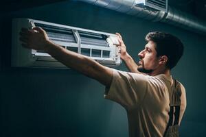 Technician installs air conditioning unit in residential space during daylight hours photo