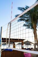 Beach volleyball net set up in a tropical location during sunset with palm trees in the background photo