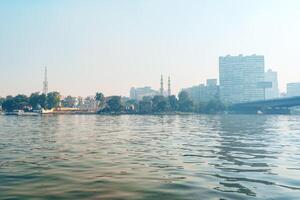 City skyline reflecting in the river during hazy daylight with modern and traditional architecture photo