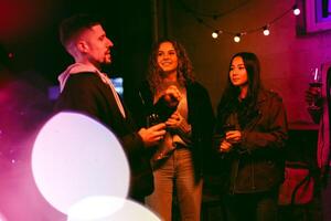 Friends enjoying an evening gathering with drinks and laughter under string lights at an outdoor location photo