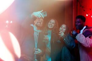 Friends enjoying a night out, taking selfies, and celebrating a special occasion at a lively venue with colorful lights photo