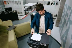 Office worker using a multifunction printer to scan documents in a modern workspace during the day photo