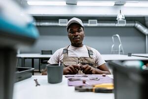 Skilled technician performing assembly work in a modern workshop while focused on tools and materials during daytime photo