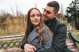 Couple enjoying intimate moment on park bench during cool weather photo