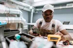 Technician conducting electrical tests with tools and smartphone in modern workshop environment photo