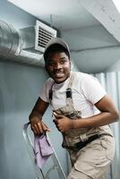 Worker smiling while on ladder, preparing for home maintenance in a cozy indoor space during daylight hours photo
