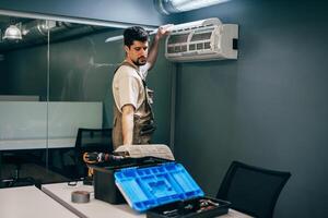 Technician installs air conditioning unit in modern office space during daylight hours photo