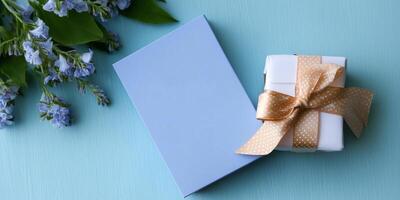 Thoughtfully wrapped gift next to blank card and fresh flowers on blue background for special occasions photo