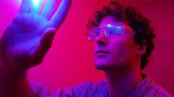 Man wearing protective glasses interacts with glowing light in a colorful indoor space during an experimental session photo