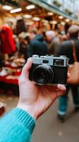 Holding a vintage camera in a bustling market with various shoppers in the background photo
