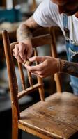 Craftsman working on a wooden chair repair in a workshop during daylight hours photo