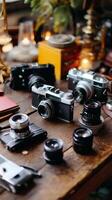 Collection of vintage cameras and lenses arranged on a rustic wooden table in a cozy workshop during a sunny afternoon photo