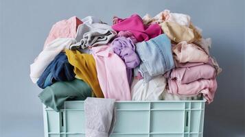 Piled laundry in a storage bin waiting to be sorted and folded in a home setting photo