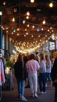 People explore a vibrant marketplace filled with lights and local crafts during the evening in a repurposed industrial space photo