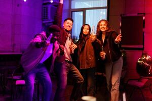 Friends celebrating joyfully at a vibrant nighttime gathering with drinks in a festive setting photo