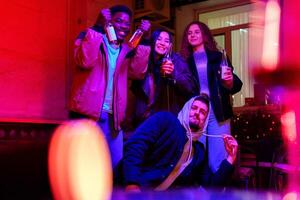 Friends celebrate with drinks in a lively indoor setting during a colorful evening gathering photo