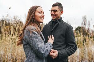 Couple enjoys a romantic moment by the water on a cool autumn day surrounded by nature photo