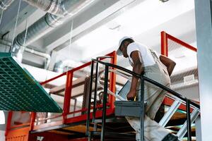 Worker ascending stairs with toolbox in modern industrial workspace during daytime hours photo