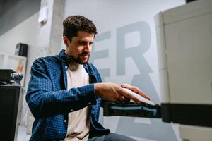 Man working diligently on printer equipment in modern office space during daytime photo