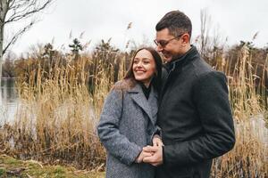 Couple enjoys a romantic moment by the lakeside during a cloudy day in autumn photo