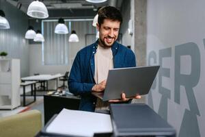 Man working on laptop in modern office space during daytime photo