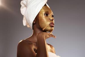 Woman applying gold facial mask during skincare routine in a calming environment photo
