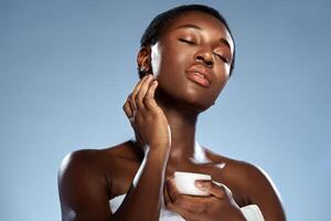 Model applying skincare product while enjoying natural light in a serene setting photo