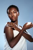 Woman applying skin cream during a skincare routine with a soft towel in a calming studio environment photo