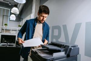 Man operating office printer while preparing documents in modern workspace during daytime photo