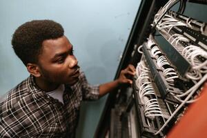 Young technician working on networking cables in a server room during daylight hours photo