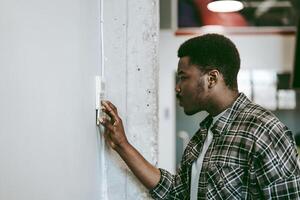 Man adjusting thermostat in modern office space during daytime while focused on energy efficiency photo