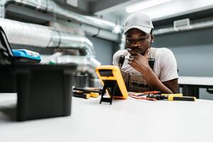 Young technician analyzes readings on a multimeter in a modern workshop during a training session photo